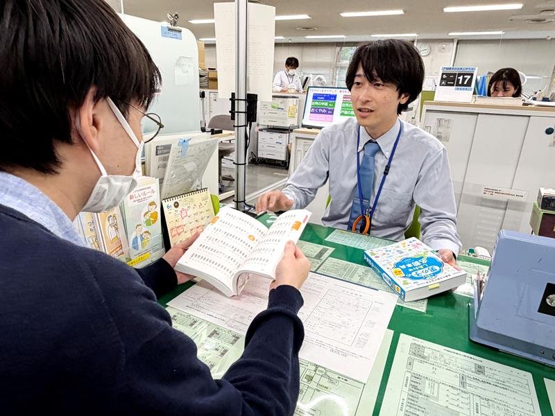 出生届の名のフリガナについて、名付け辞典を手に窓口で説明する北川さん＝６月上旬、船橋市役所
