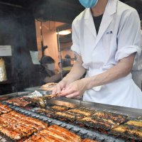 土用の丑の日の２８日、成田山参道では参拝客の食欲をそそるかば焼きの香ばしい煙が広がった。老舗「川豊」では、客が静かにうな重を頬張りながら顔をほころばせた＝成田市