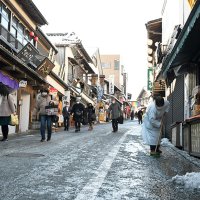 成田山参道の坂道で凍結した雪をかく店員。足を滑らせる参拝客の姿もあった＝７日午前１０時５５分ごろ、成田市