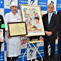 完成した防犯ポスターの前で、署長感謝状を受け取ったさとうさん（左から２人目）。多忙な連載の合間を縫い、すし職人の衣装で駆け付けた
