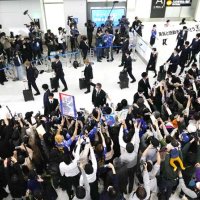 サッカーＷ杯カタール大会を終え、帰国した日本代表（上）と出迎える大勢の人たち＝７日、成田空港（共同）