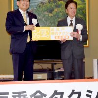 社会実験中を示すマグネットプレートを関口社長（右）に贈る神谷市長