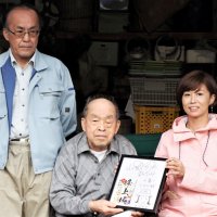 記念の額装を山城ガールむつみさん（右）から贈られる峰上城主の末裔、石井博さん（中央）と秀幸さん＝富津市
