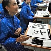 ５年生の教室で書道に挑戦し「友」という字を書き上げて笑顔のタイの小学生
