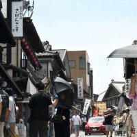 厳しい暑さの中、日傘をさす観光客らが歩く成田山参道＝７日午前、成田市