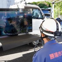 ドローン映像をモニターで確認する照川市長ら