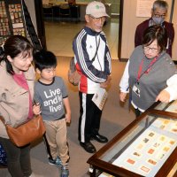 ミュージアムトークで、来館者にマッチラベルの魅力を解説する島立さん（右）＝１５日、千葉市中央区の県立中央博物館