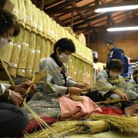 成田山新勝寺のお堂に飾り付ける細いわらの束を器用に編み込む奉仕員たち＝１日、成田市