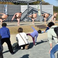 相撲体操で体を温める力士や参加者
