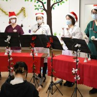 入院中の子どもと保護者の前でハンドベルの演奏を披露する病院スタッフ
