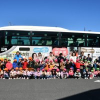 ラッピングのデザインが一新し、高速バスの前で記念撮影する園児ら＝２１日、多古町