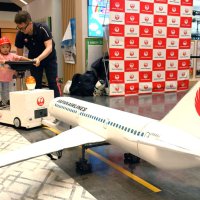 航空機の模型をミニけん引車でプッシュバックする子ども