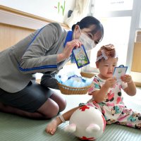 ＡＮＡ客室乗務員の阿部さんからスズランの香りが付いたしおりを受け取り興味津々の日葵ちゃん

