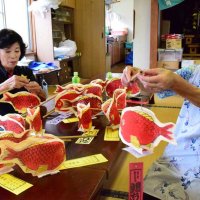 鯛ちょうちんに持ち手の竹を付ける女性＝２６日、茂原市茂原の八坂神社