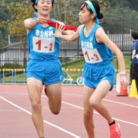 市船橋の２区・横山桃花（左）がトップで３区・藤重桃子へたすきをつなぐ＝東総運動場