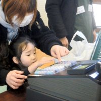 スーパーマーケット経営会社のブースでレジ打ちを体験する児童ら＝横芝光町