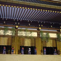 成田山新勝寺の大本堂軒下に一列になって長いササ竹を揺する職員＝１３日午前６時ごろ、成田市
