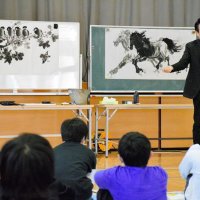 児童の前で水墨画を描き、特徴を説明する王さん＝茂原市立茂原小
