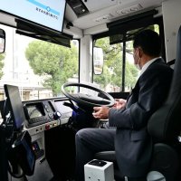 カーブを曲がる自動運転バス。運転手はハンドルから手を離している
