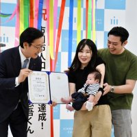 「５０万人目」になった真境名悠吾ちゃんと両親。左は田中市長＝８日、市川市役所