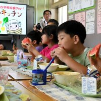 五十嵐市長（左）とスイカ給食を楽しむ富里第一小学校の児童＝１７日、富里市
